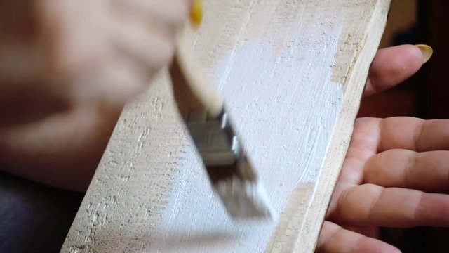 painting a wooden board with a white paint brush close-up