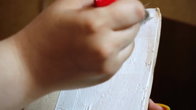 painting a wooden board with a white paint brush close-up