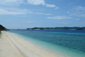 背景に島のある白い砂浜とエメラルドグリーンの海