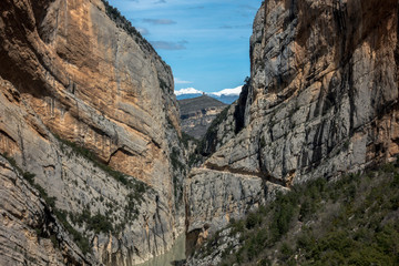 Trekking route through mountain cliffs with snowy peaks in background