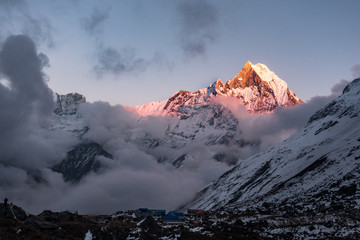 Macchapucchre Himalayan Peak at red and orange sunset with clouds