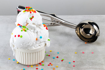 plate of vanilla ice cream scoop swith sprinkles and waffle cones