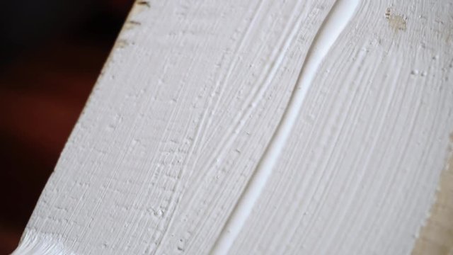 painting a wooden board with a white paint brush close-up