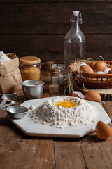 Flour with yolk egg and A lot of eggs put in the basket are place on the wooden table for cooking something.