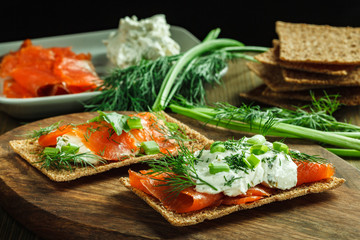 Snacks with salmon, creamy cheese, green onion and dill on rye crisps