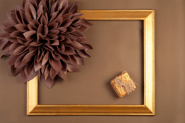 A large brown flower from EVA foam, on a brown background with a golden frame.