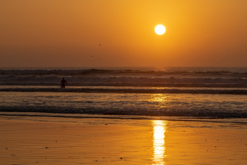 Silhouette of a person walking into the sea at sunset over the Atlantic Ocean from Agadir beach, Morocco