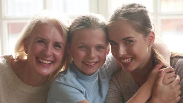 Happy old grandmother, young mother and child daughter embracing smiling