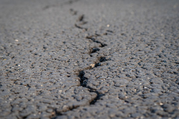 terrible crack in the road pavement, close up blurry background
