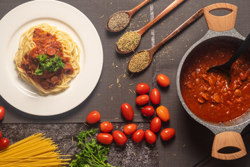overhead view of a plate of spaghetti served with the beef tomato sauce with ingredients on the mat.
