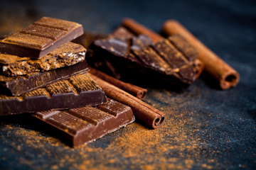 Chocolate bars pieces heap witn cinnamon powder and sticks.