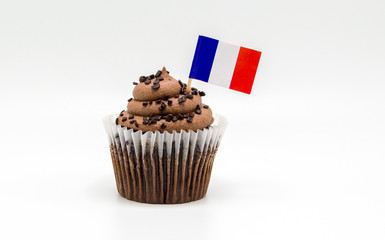 chocolate swirl cupcake with a small French flag toothpick isolated on white