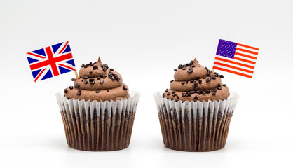two chocolate swirl cupcakes with small British and American flag toothpicks isolated on white
