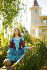 girl animator dressed as a medieval princess on the background of the castle in a beautiful park