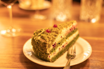 Piece of spinach cake with white cheese cream and decorated with cranberries
