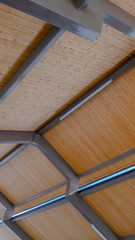 Vertical Looking up at the roof of a pavilion with brown wooden planks and gray frames