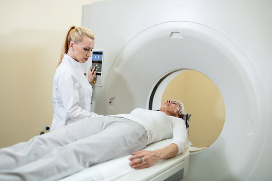Radiologist ad mature patient during CT scan procedure.