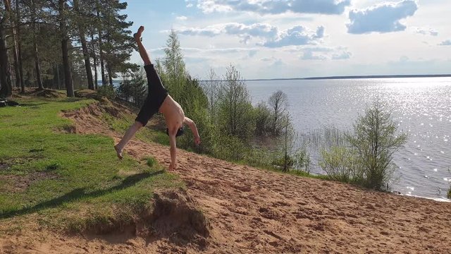 Somersault off a cliff. Man doing flips on the sand slow motion