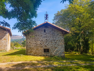 Fototapeta na wymiar Church of San Donato in the valley of Araiz with the mountains of Aralar from the area of Betelu, Navarra. Spain