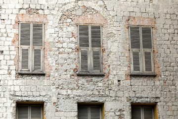 Fototapeta na wymiar The stone facade with closed shutters on windows