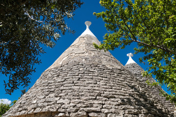 Fototapeta na wymiar Unos tejados cónicos de piedra de trullos, construcción medieval en Alberobello, en Italia