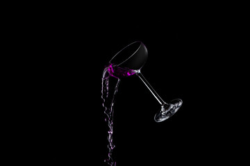 cocktail pouring out of a glass on a black background