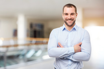 Obraz premium Smiling businessman stands in the business center with crossed arms