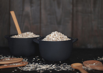 oatmeal in ceramic pots for baking close-up. oatmeal in pots and wooden spoons close-up on the table.