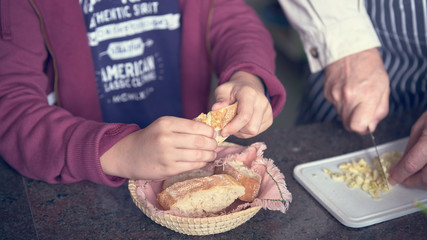 Photograph of a child holding bread while his family cooks. Huelva, España.
