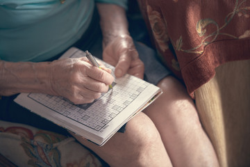 Photograph of an elderly woman doing crosswords at home. Huelva, Spain.