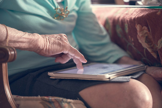 Photograph of an old woman reading newspaper on the tablet. Huelva, Spain