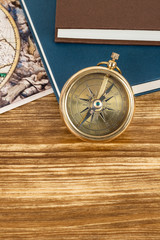 Compass on wooden background with vintage book and map, concept for direction transportation and travel, with copy space