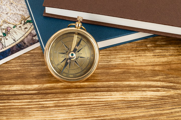 Compass on wooden background with vintage book and map, concept for direction transportation and travel, with copy space