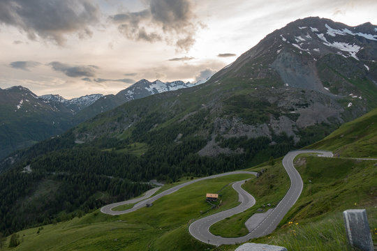 Empty alpine road during sunset with glacier and mountains in background
