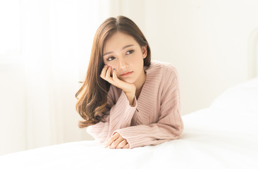 Woman indoor portrait. Closeup of pensive young Asain woman in warm knitted pink clothes in the...
