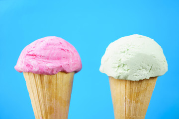 Strawberry and pistachio ice-cream scoops in waffle ice cream cones on pastel background. Summer, heat, vacation,choice, refreshment, traditional seasonal cold sweets