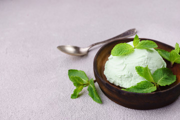 Mint ice cream scoop and peppermint leaves on stone table, copy space. Food background, summer refreshing concept, traditional seasonal cold sweets