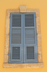 Large window with closed blue wooden shutters