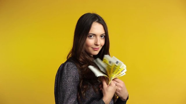 Carefree young woman counting euro banknotes and show stack of money in hand