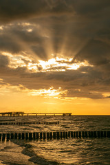 colorful seaside view with sea bridge and sun rays breaking through the sky
