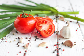 Fresh tomatoes with spices. Organic healthy food on wooden background. Green garlic. Summer and autumn vegetables.