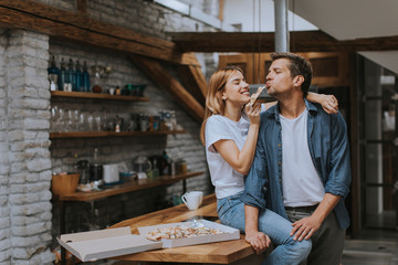 Young couple in love eating pizza in the rustic home