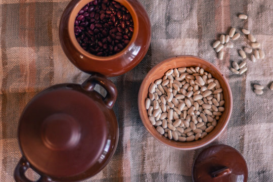 White beans in a clay deep plate on a linen tablecloth among clay pots, soft focus © Анастасия Гайкова