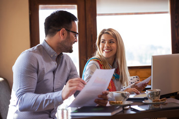 A beautiful young business woman feels loving when she looks at her handsome colleague while working together on a project in front of a laptop.