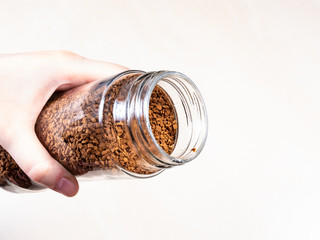 hand holding open glass jar of instant coffee