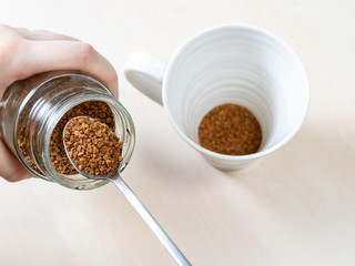 spooning up portion of instant coffee over mug
