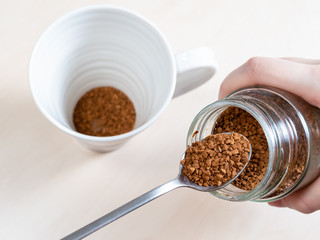 spoon near glass jar with instant coffee over mug