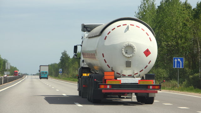 Semi Truck With Propane Tank Moving On Asphalt Road On A Summer Day - ADR Dangerous Cargo, Side Rear View