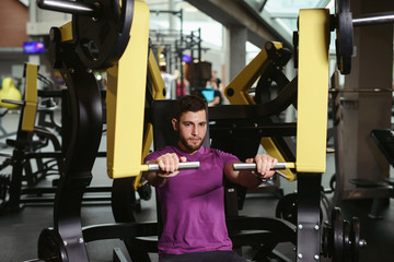 Man exercising at gym. Fitness athlete doing chest exercises on vertical bench press machine