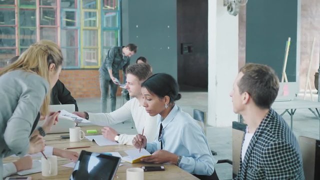 A business team is discussing a project at a large office table. Creative office interior. Coworking. Office workers